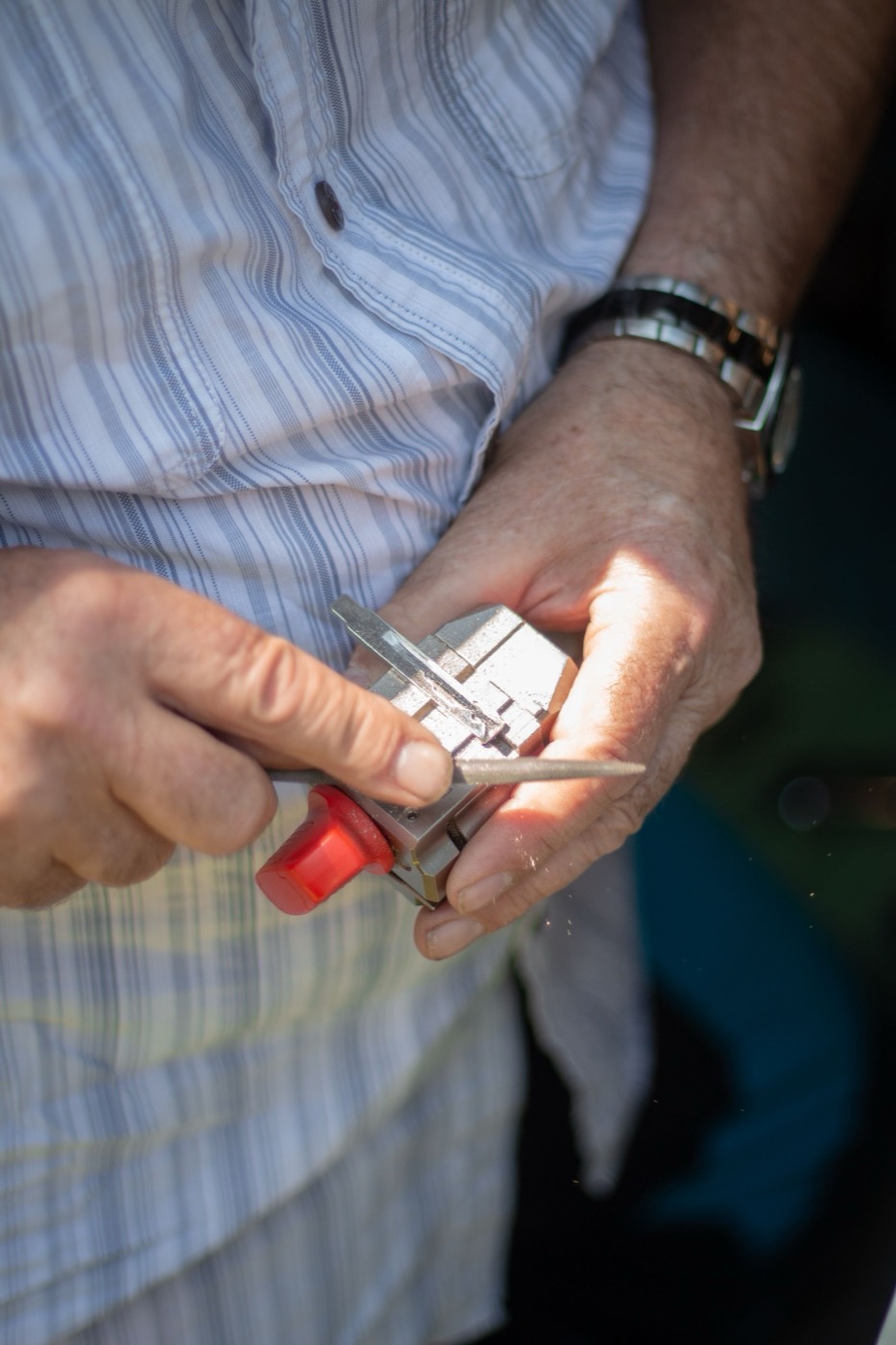 Locksmith filing a car key blade on a hand-held key-cutting tool