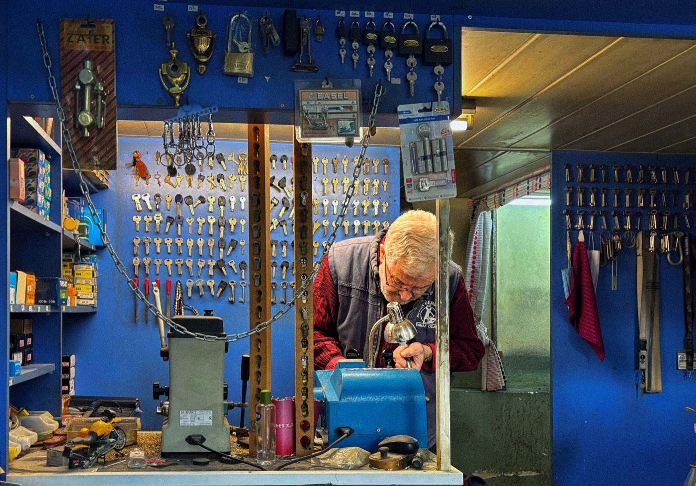 Wall of key blanks and a locksmith working at the key-cutting bench in the shop